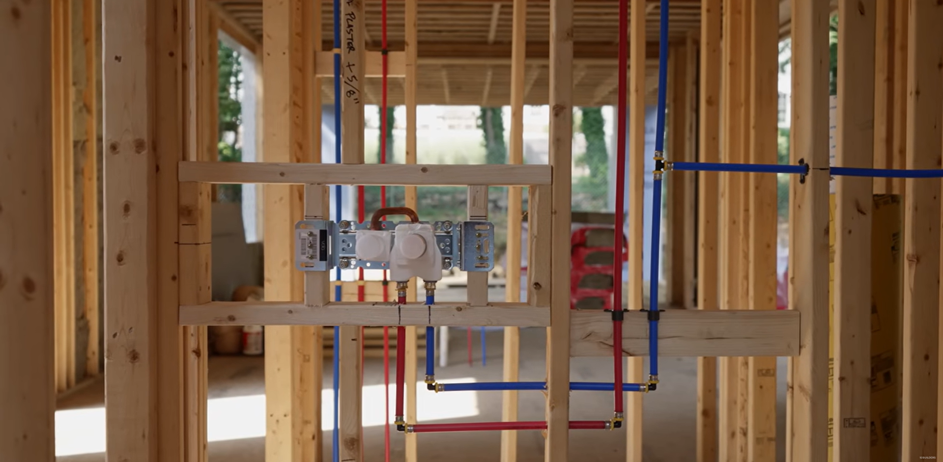 Color-coded PEX supply lines run across joists and studs