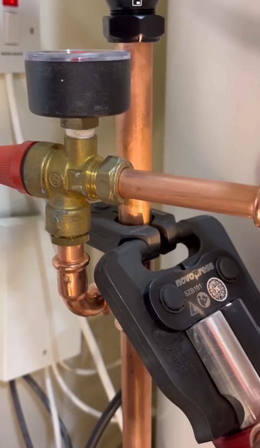 Plumber making a press-fit connection on copper pipe near a shutoff valve
